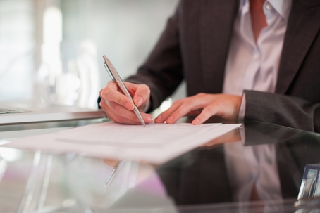 woman writing on paper at desk