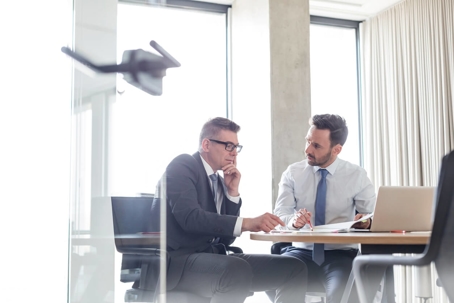 Businessmen reviewing and discussing report in conference room