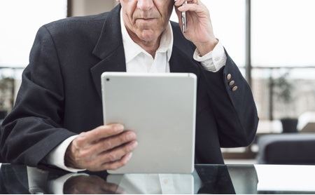 Man talking on mobile phone while looking at a tablet.